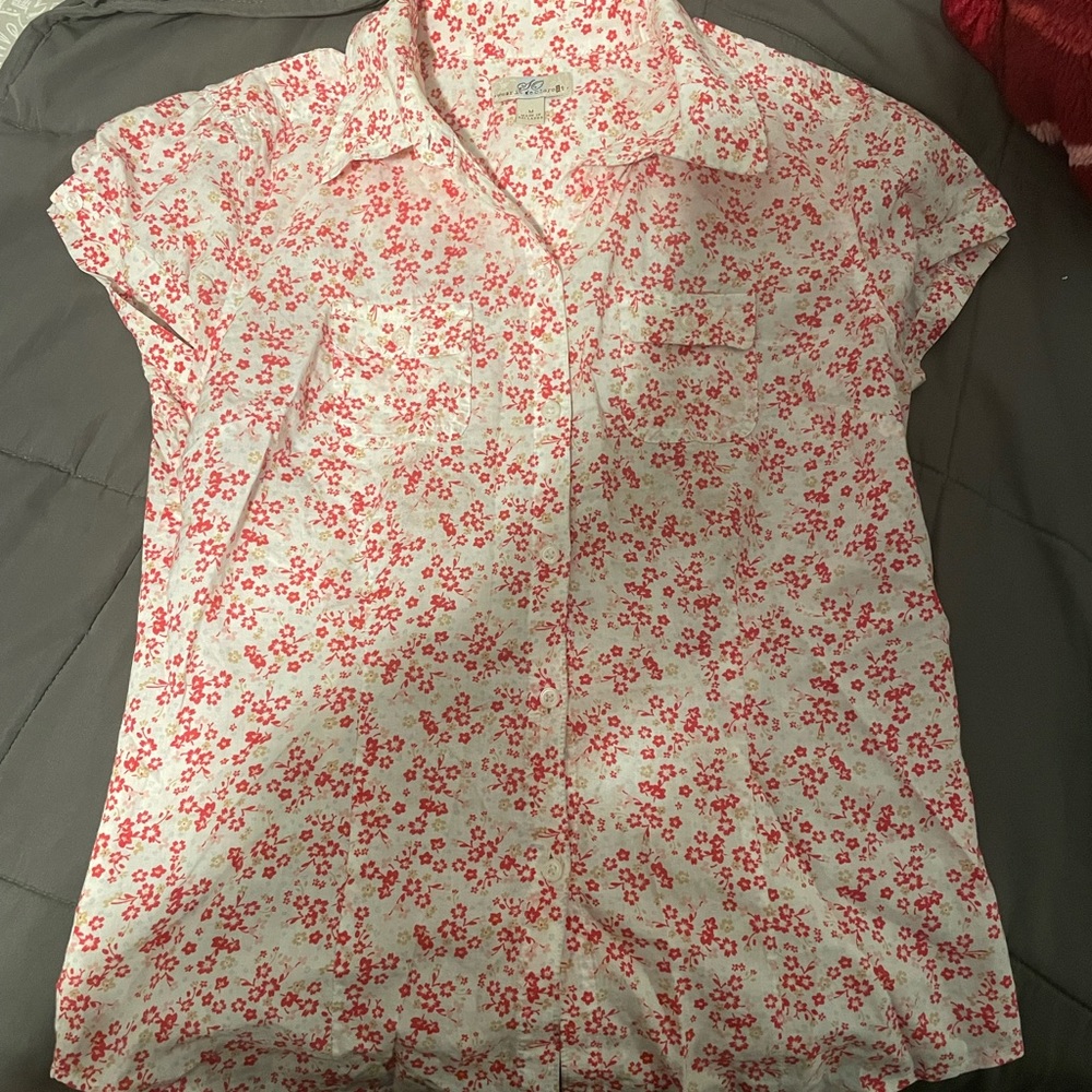 A white blouse with pink flowers. Short sleeve, tight fitting.